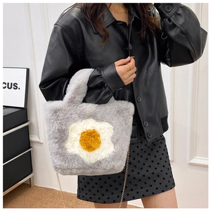 Detail of grey plush tote bag with egg motif and gold chain strap on model