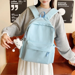 Detail of light blue backpack with fine grid texture and cute plush cloud pendant