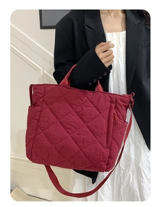 Detail showing deep red quilted tote bag with diamond stitching and adjustable strap