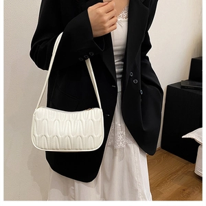 Detailed macro of white quilted wave pattern on a trendy French style baguette bag