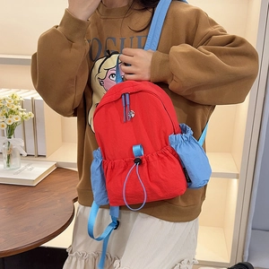 Detailansicht des rot-blauen Nylon-Rucksacks mit strapazierfähiger Seitentasche und Webetikett
