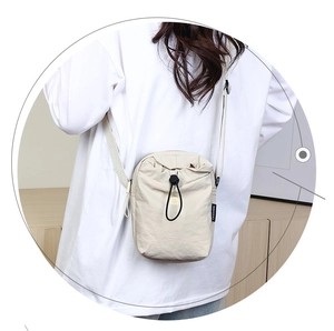 Dettaglio borsa a tracolla in nylon beige con coulisse nera ed etichetta alla moda