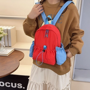 Detailansicht des rot-hellblauen Nylon-Rucksacks mit Schnalle und Kordelzugtasche
