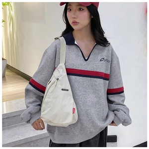 Detail of minimalist cream nylon crossbody bag with red FASHION tag on adjustable strap
