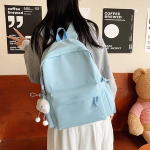 Detail of light blue canvas backpack with cute cloud charm and functional side pockets