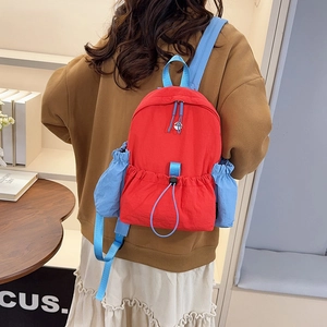 Detailansicht des roten und hellblauen Nylon-Rucksacks mit Kordelzugtasche und Reißverschluss