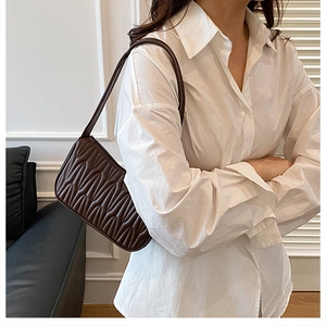 Detail view of dark brown French mini baguette bag with elegant pleated wave texture finish