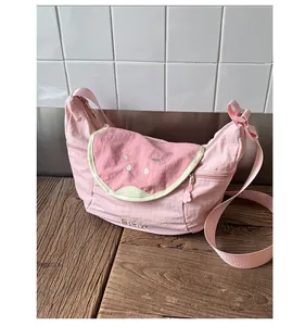 Close-up of pink guava crossbody bag with fruit embroidery and cute cat paw zipper pull