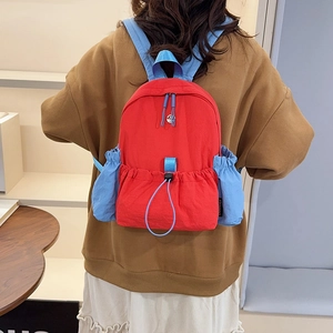 Detailansicht des rot-blauen Nylonrucksacks mit Markenetikett und praktischer Seitentasche