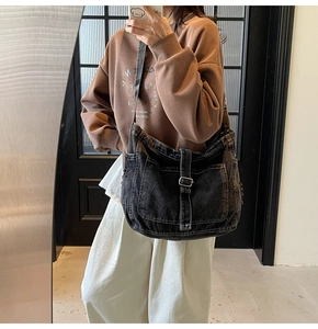 Detail showing distressed black denim tote bag with contrast stitching on casual outfit
