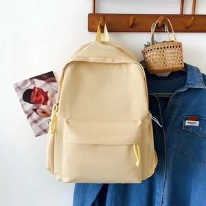Detail of light yellow plaid backpack with nylon fabric texture and front pocket