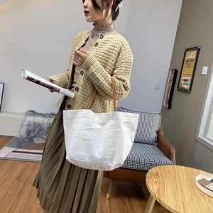 Minimalist white canvas bucket bag with brown handles and large capacity shown on model