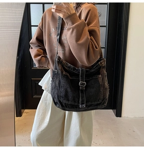 Detailed view of the oversized black denim crossbody bag with retro utility pockets