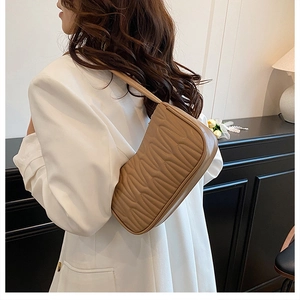 Close-up of light brown pleated leather underarm bag with elegant quilted wavy texture