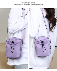 Dettaglio della borsa a tracolla in nylon lilla con coulisse nera ed etichetta di moda