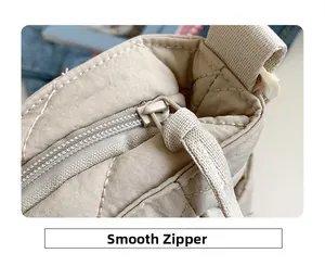 Close-up of smooth zipper closure on beige quilted nylon tote bag with neat stitching