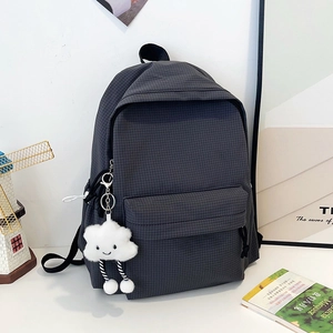 Detailed close-up of dark grey checkered backpack with a cute white cloud plush charm