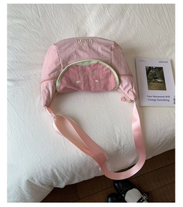 Pink semi-circular crossbody bag with guava embroidery and paw-shaped zipper detail