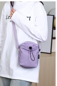 Dettaglio di una mini borsa a tracolla in nylon viola con coulisse e zip di chiusura