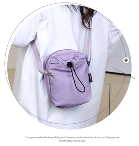 Dettaglio della borsa a tracolla in nylon lavanda con chiusura a coulisse e etichetta moda