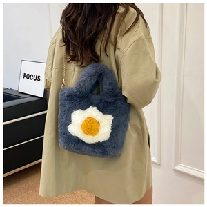 Detailed macro view of the blue plush material and fluffy fried egg design on the handbag