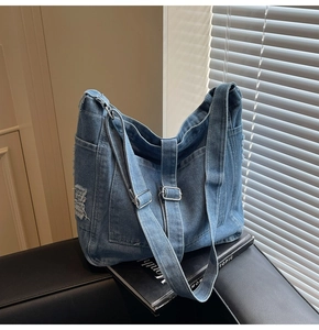 Detail of vintage washed denim tote bag showing side pocket and metal buckle strap