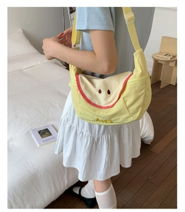 Detail view of yellow apple shaped nylon crossbody bag with adjustable strap on model