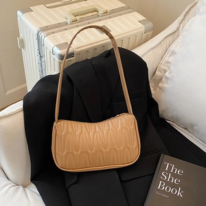 French style khaki baguette bag with quilted wave pattern on a black blazer
