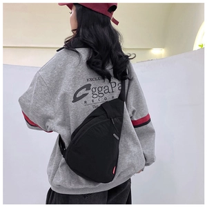 Detailed view of durable black nylon crossbody chest bag with red woven side label