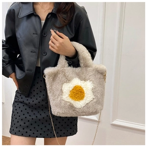 Detail of soft cream plush bag featuring a fried egg design and gold chain strap