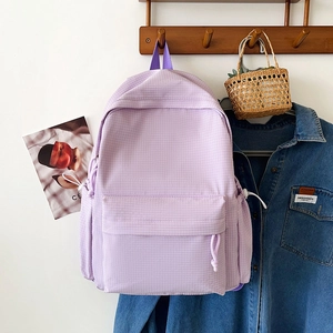 Detail of light purple checkered backpack hanging on a rack with drawstring closure