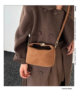 Détail du sac à bandoulière en daim marron avec boucle dorée élégante sur le mannequin