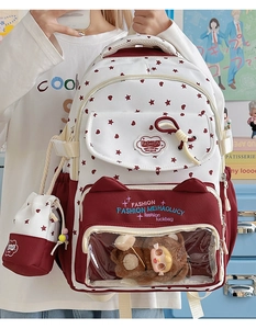 Detail of white star print backpack with transparent heart window and plush bear accessory