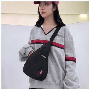 Detail of black nylon chest bag with red fashion label on casual female model
