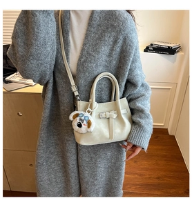 Detail of cream crossbody bag with belt buckle decoration and cute plush dog charm