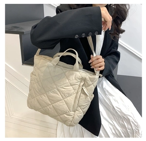 Detail of beige quilted tote bag with side zipper pocket and adjustable strap