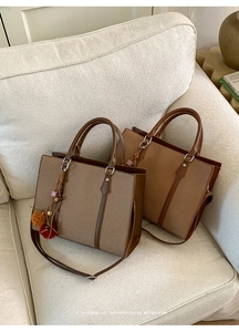 Detail der Webstruktur und des Ledergriffs einer braunen Retro-Tasche mit flauschigem Anhänger