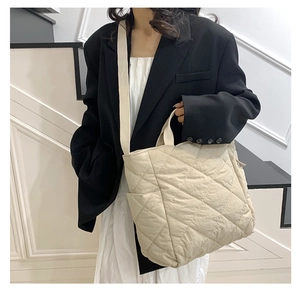 Detail of beige quilted tote bag with diamond stitching and adjustable wide shoulder strap