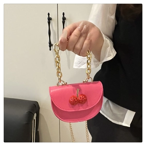 Détail du mini sac selle rose fuchsia avec chaîne dorée et ornement cerise en strass