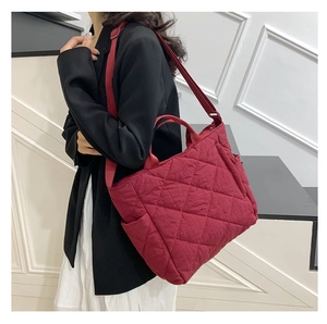Detail of burgundy quilted tote bag featuring adjustable wide strap and nylon fabric texture