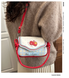 Close-up of cute blue plaid crossbody bag with apple embroidery and bow detail