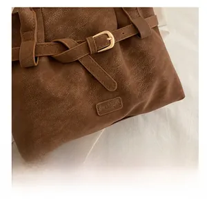 Detail shot of brown faux suede tote bag featuring litchi grain and a metal buckle strap