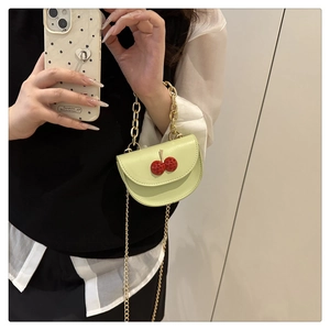 Détail du mini sac bandoulière vert clair avec décor cerises et doubles chaînes dorées