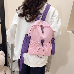 Detailansicht eines pink-violetten Nylonrucksacks an einem Modell in einem hellen Raum