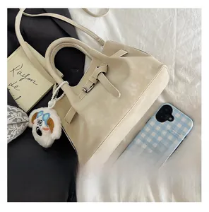 Detail of beige suede bucket bag with decorative buckle and cute white dog charm