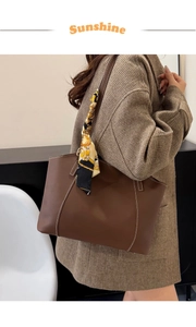 Detail of dark brown tote bag with contrast stitching and floral silk scarf on handle