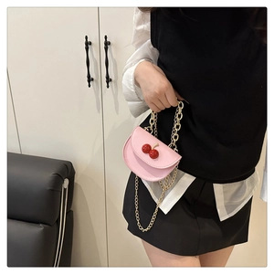 Détail d'un sac à main rose en cuir avec décor cerise et chaîne dorée élégante