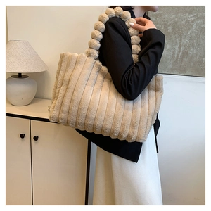Detailed view of beige plush tote bag with vertical stripes and fluffy pom-pom handles