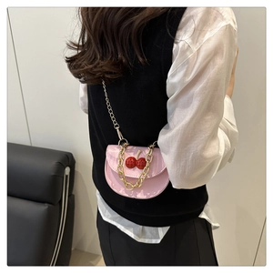 Mini sac bandoulière rose verni avec motif cerise et chaîne dorée porté par mannequin