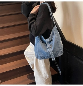 Detailed shot of vintage blue denim shoulder bag with distressed edges and metal buckles